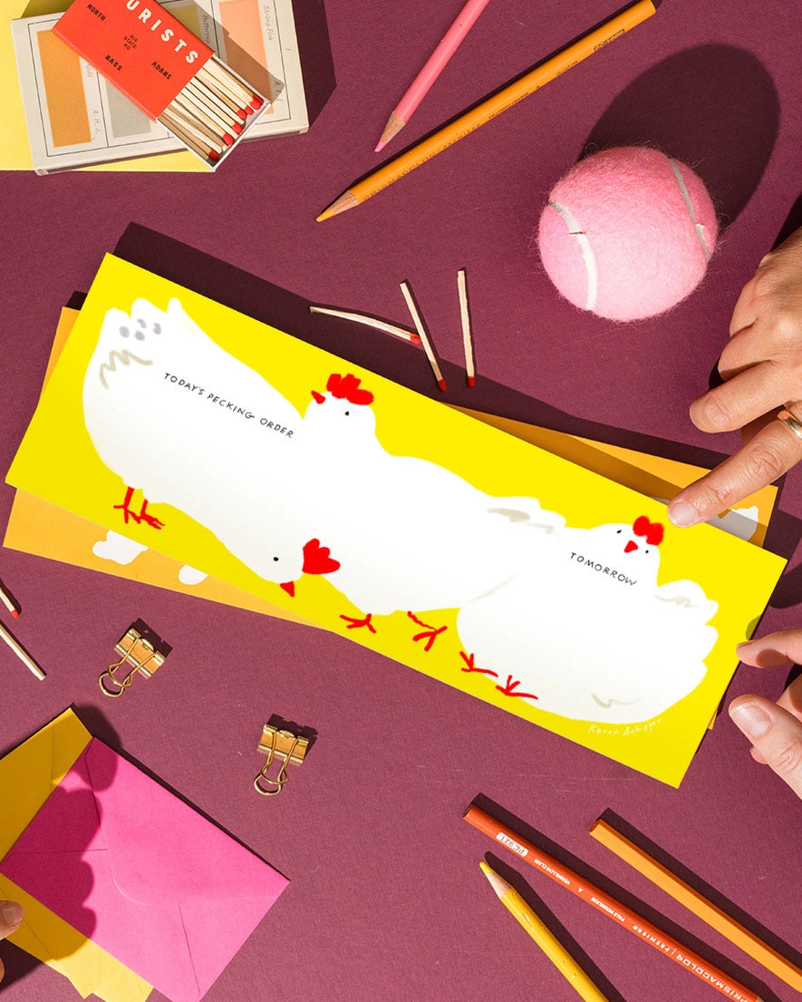 A chicken-decorated weekly notepad amongst stationery items.