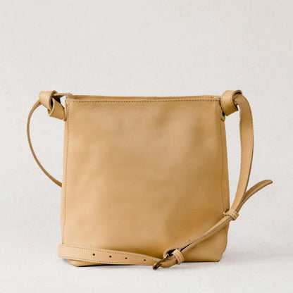 Tan leather shoulder bag on white background.