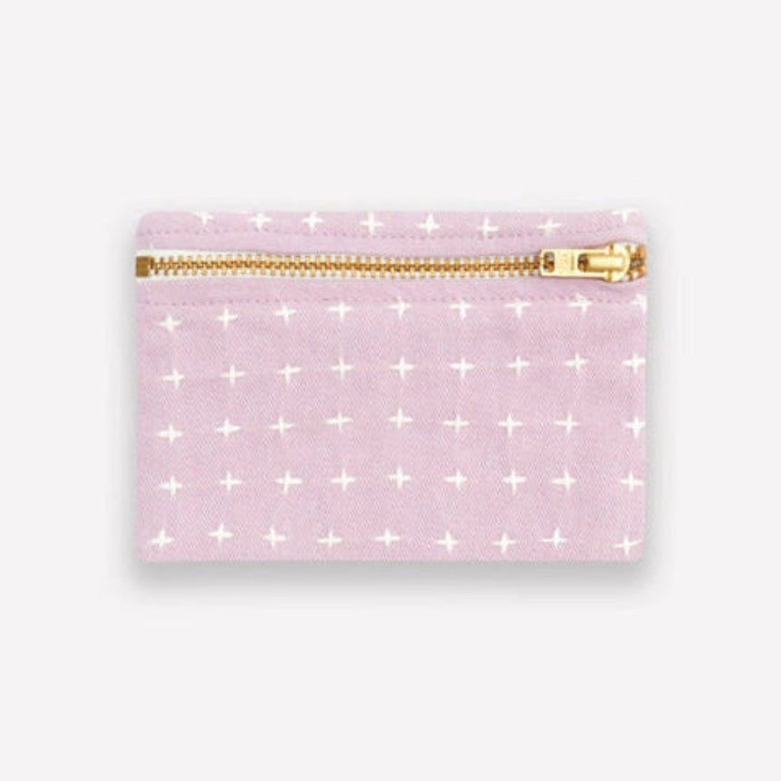 Light purple coin purse with white cross stitch pattern and gold zipper on a light gray background