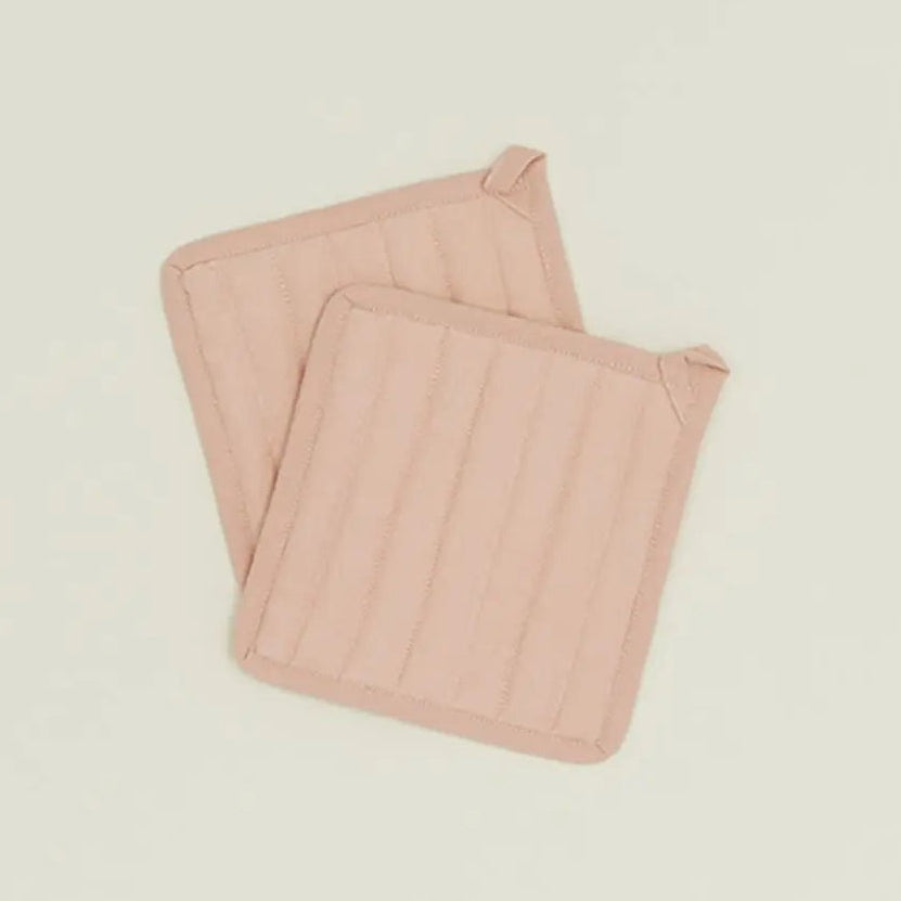 Two pink quilted pot holders on a beige background