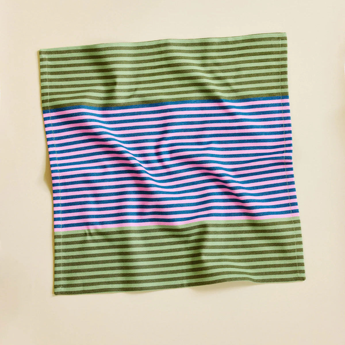 Striped fabric napkin with green, pink, and blue pattern on a beige background