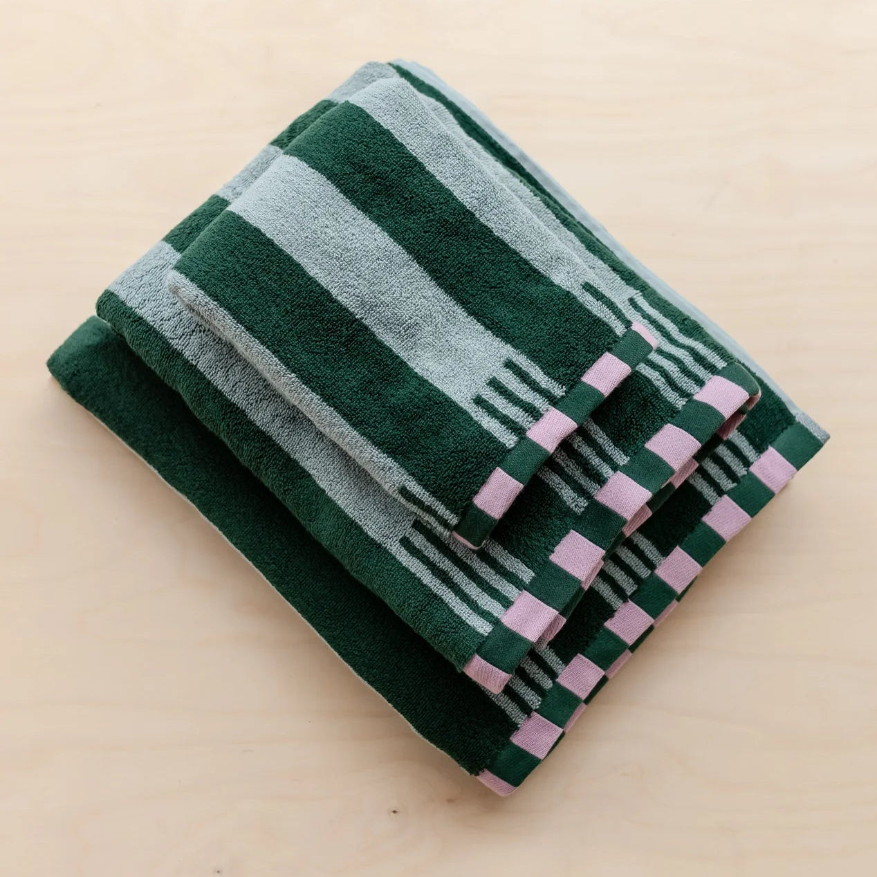 Folded green towel with geometric pattern on a beige background