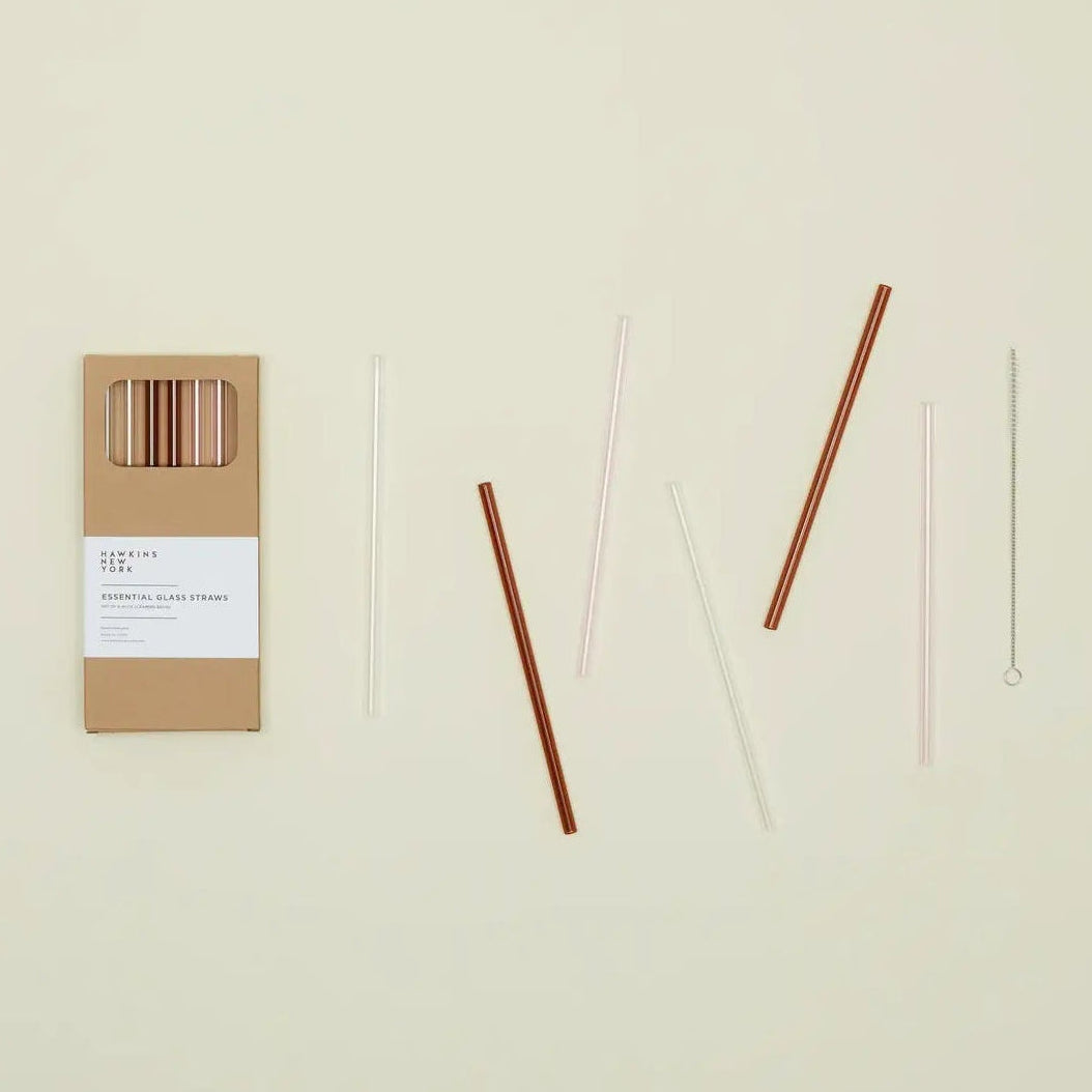 Set of six pink, amber, and clear straws with packaging on a beige background