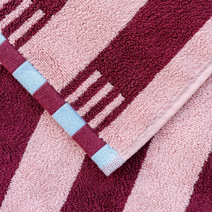 Close-up of a textured fabric with pink and red stripes and a blue square.