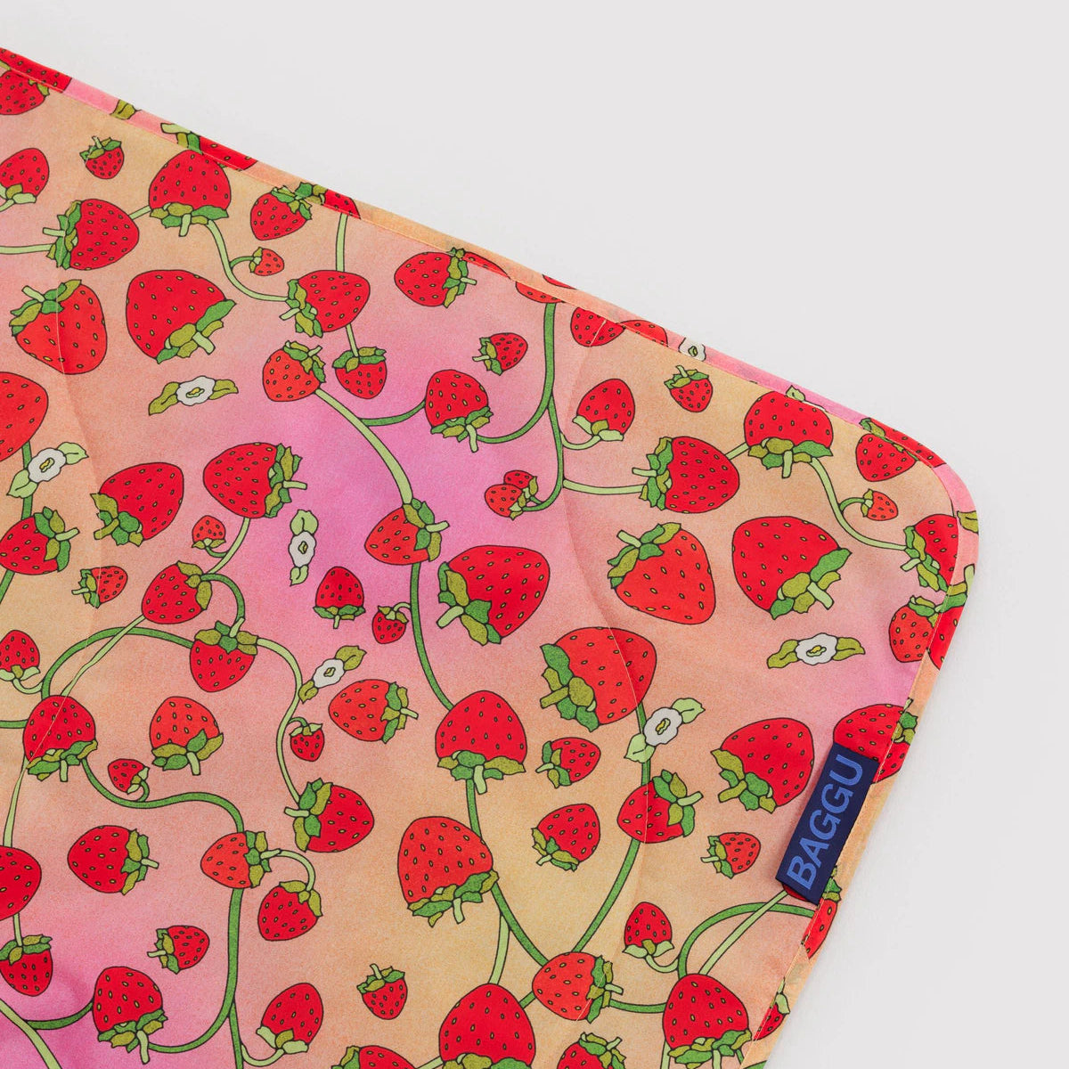 Nylon blanket corner with strawberry pattern on a light pink background