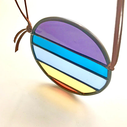 Colorful striped pendant on a brown cord against a white background