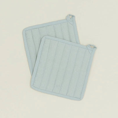 Two light blue textured trivets on a beige background