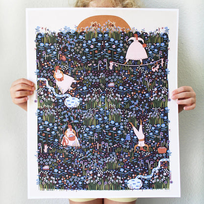 A person holding up a large white art print featuring a whimsical illustration of a dark blue wildflower field with small figures, winding light-blue streams, and a tan sun. 