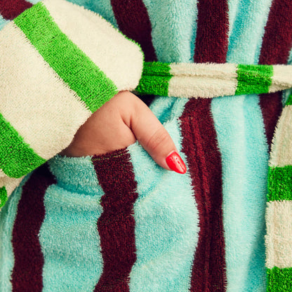 Close-up of a hand in pocket of a striped robe with green, white, blue and brown colors.