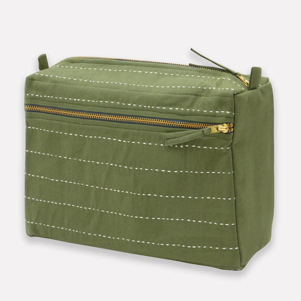 Green toiletry bag with white stitching and gold zipper on a light gray background