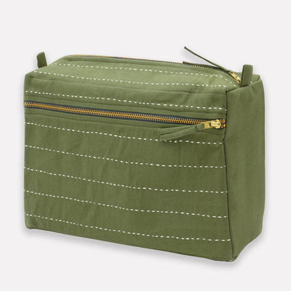 Green toiletry bag with white stitching and gold zipper on a light gray background