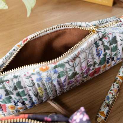 Floral-patterned pencil case with a gold zipper on a wooden surface